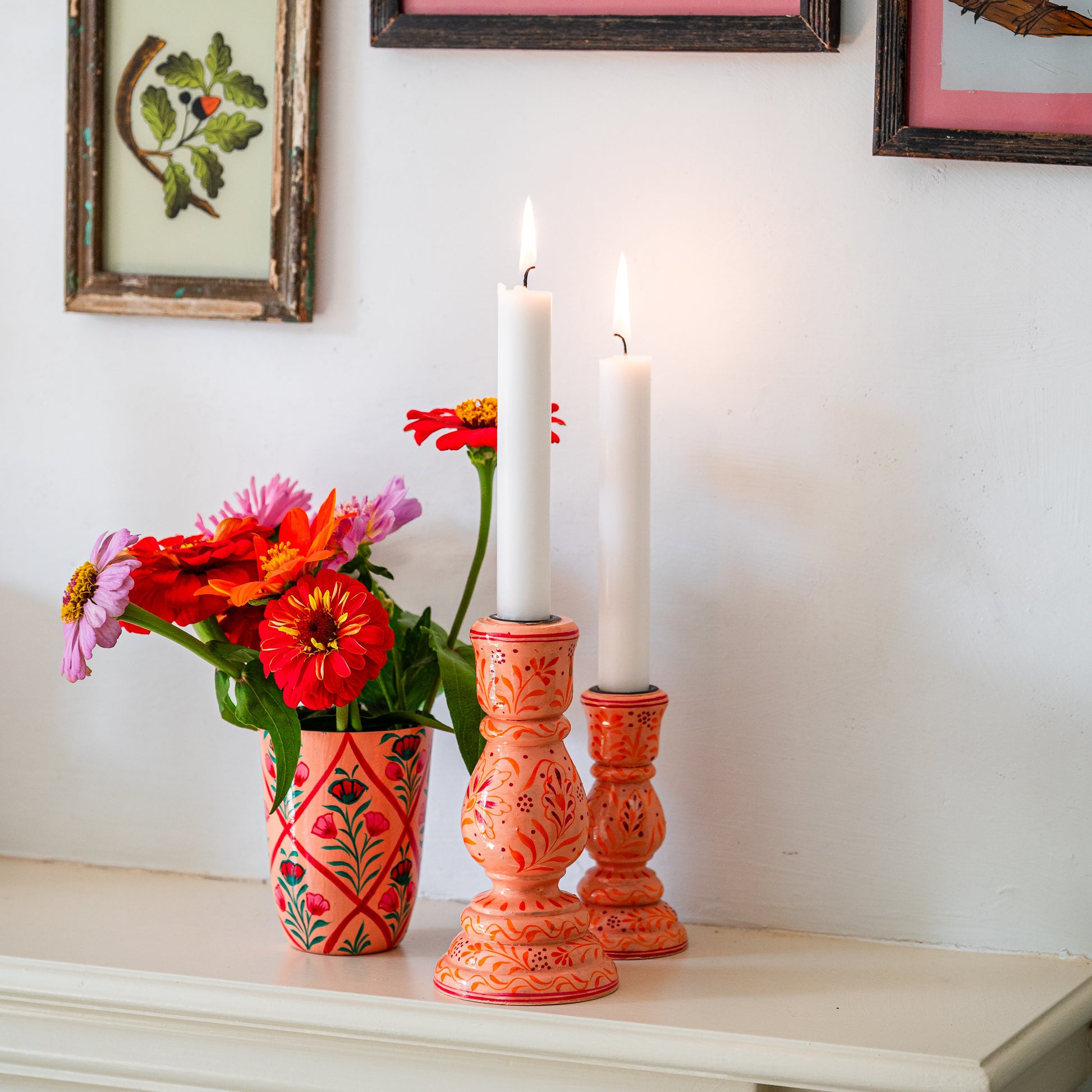 Decorative candles in ornate holders with a vase of flowers on a shelf. handpainted candle hlder coral