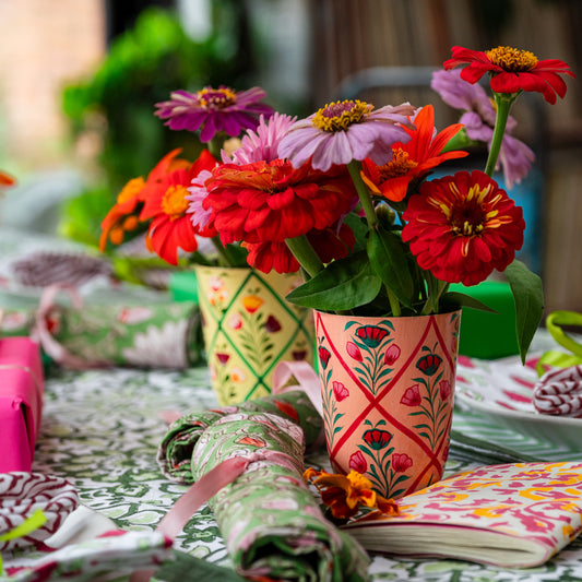 Colorful flowers in patterned cups on a table with decorative items