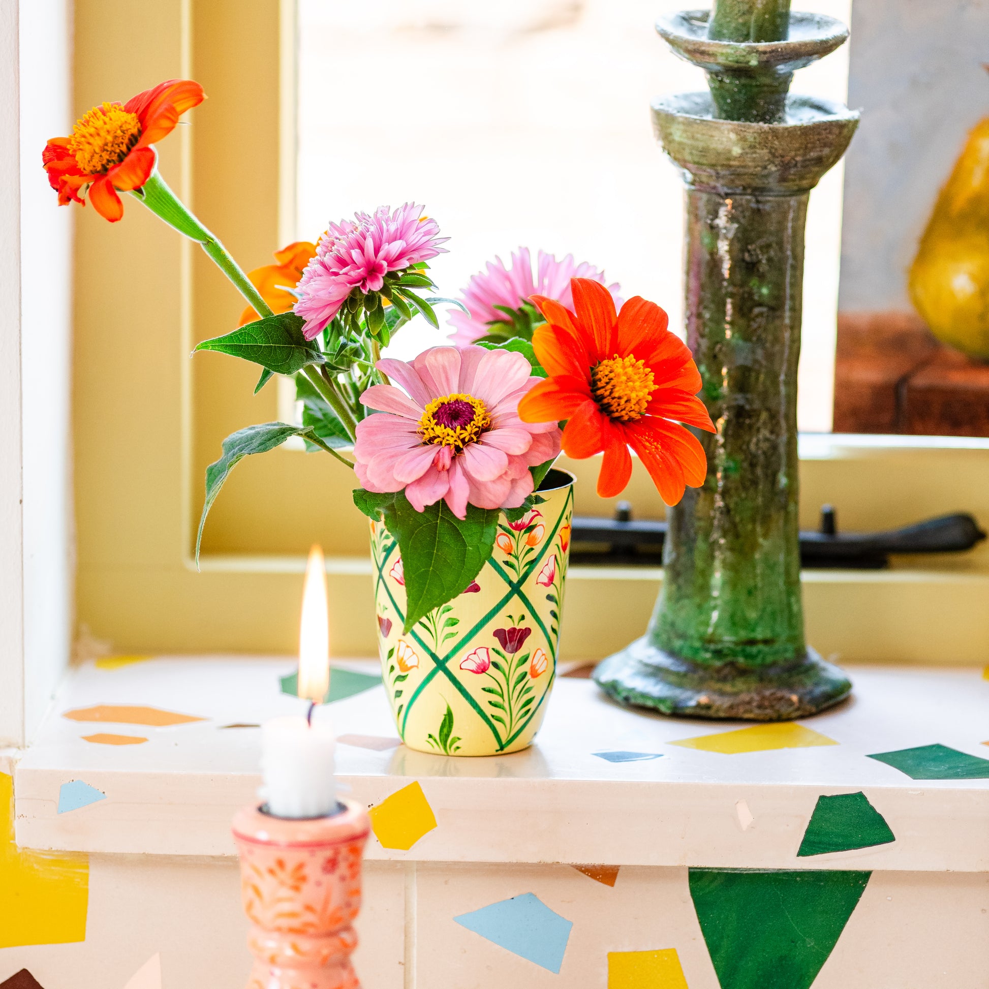 Decorative table with flowers in a vase, candles, and colorful geometric patterns. hand painted vase floral cream. Vase cream hand painted