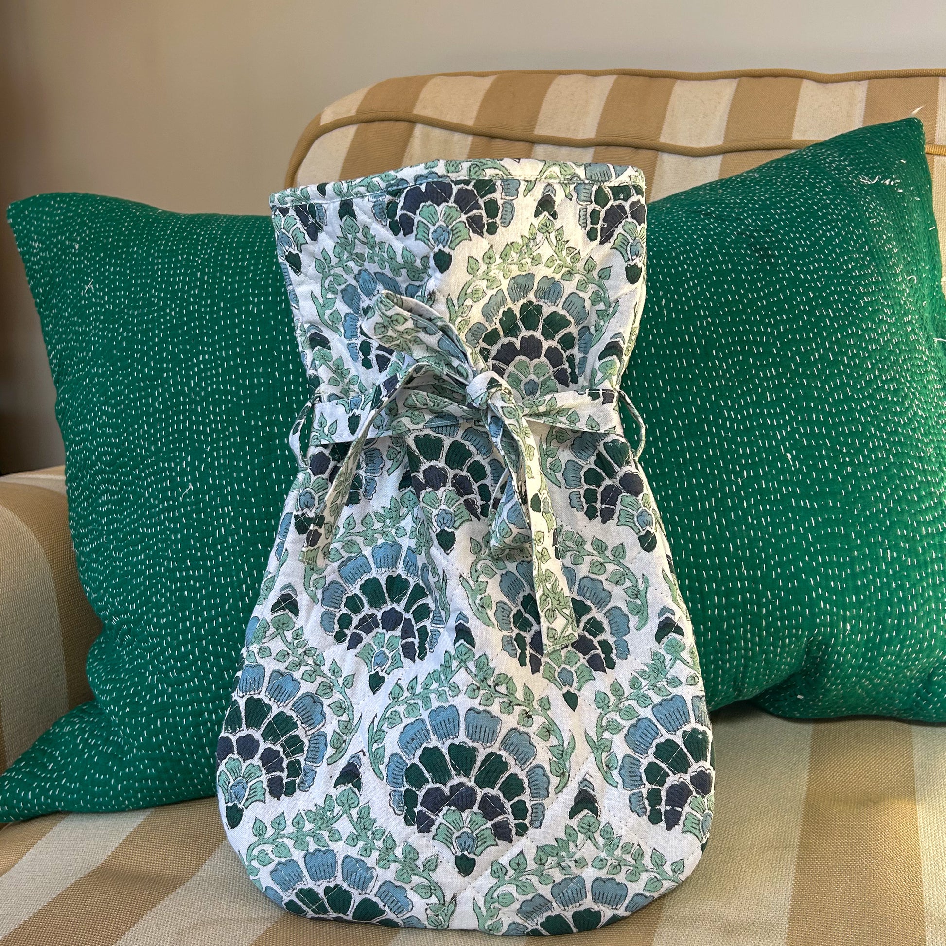 Patterned hot water bottle on a striped couch with green pillows