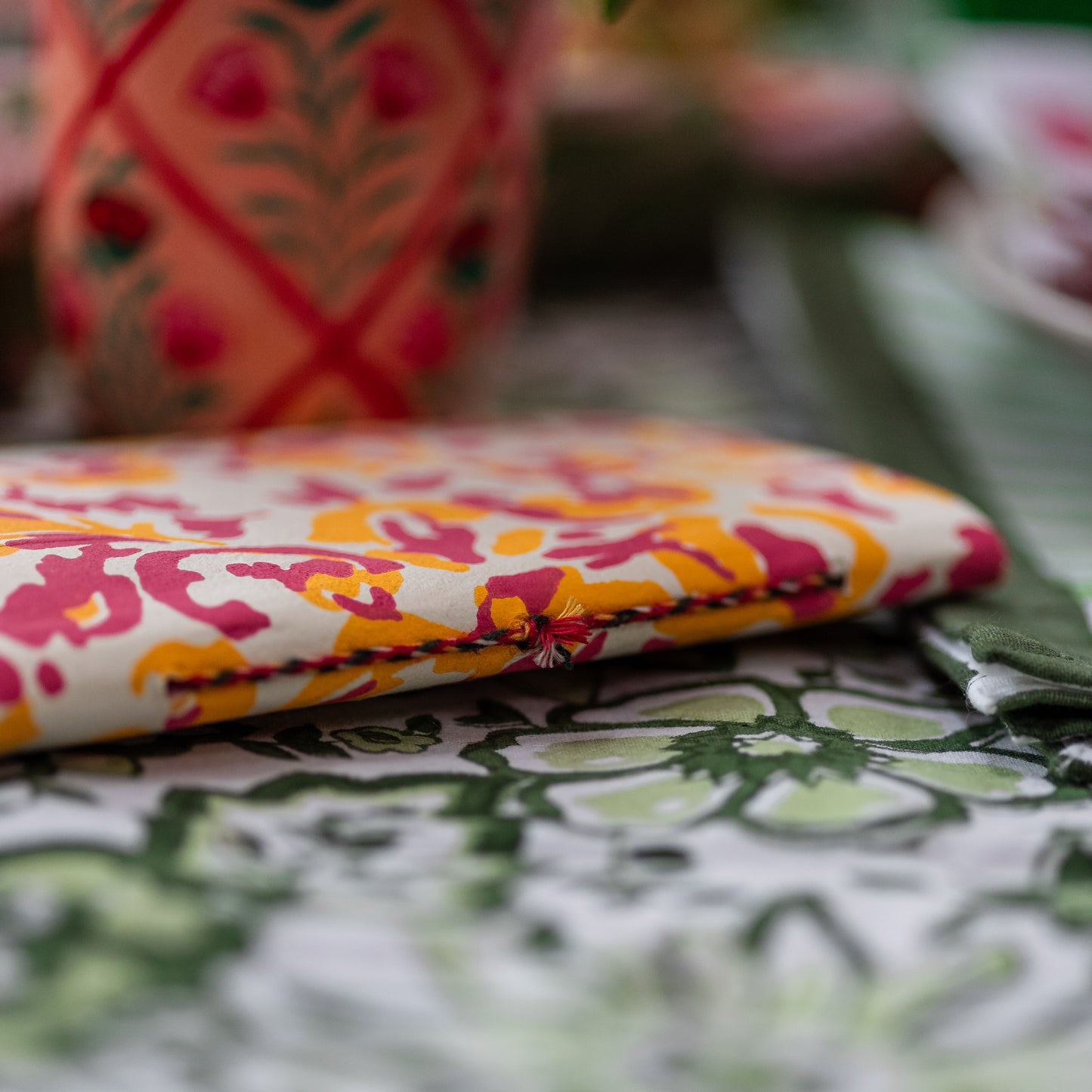 Colorful fabric with floral pattern on a table with other fabrics in the background