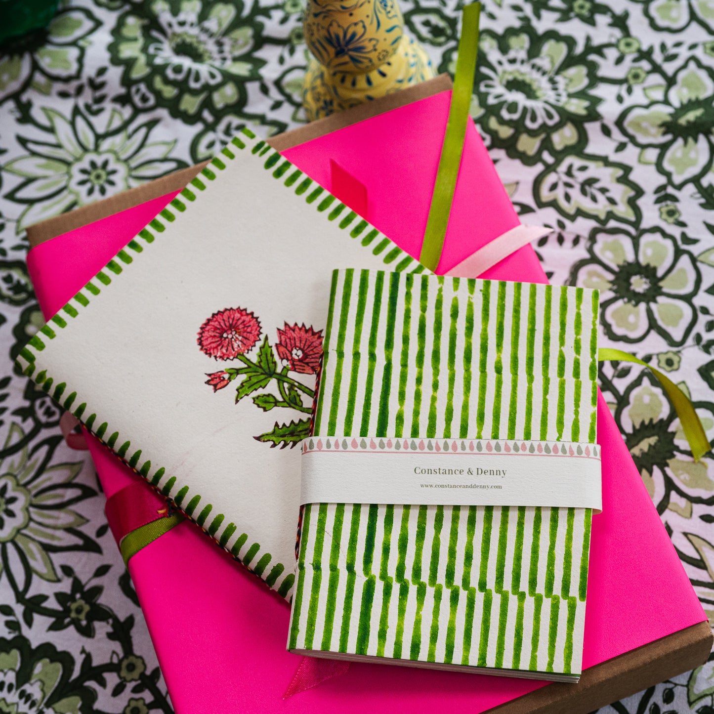Colorful stationery items including a notebook, pen, and notepad on a patterned surface.
