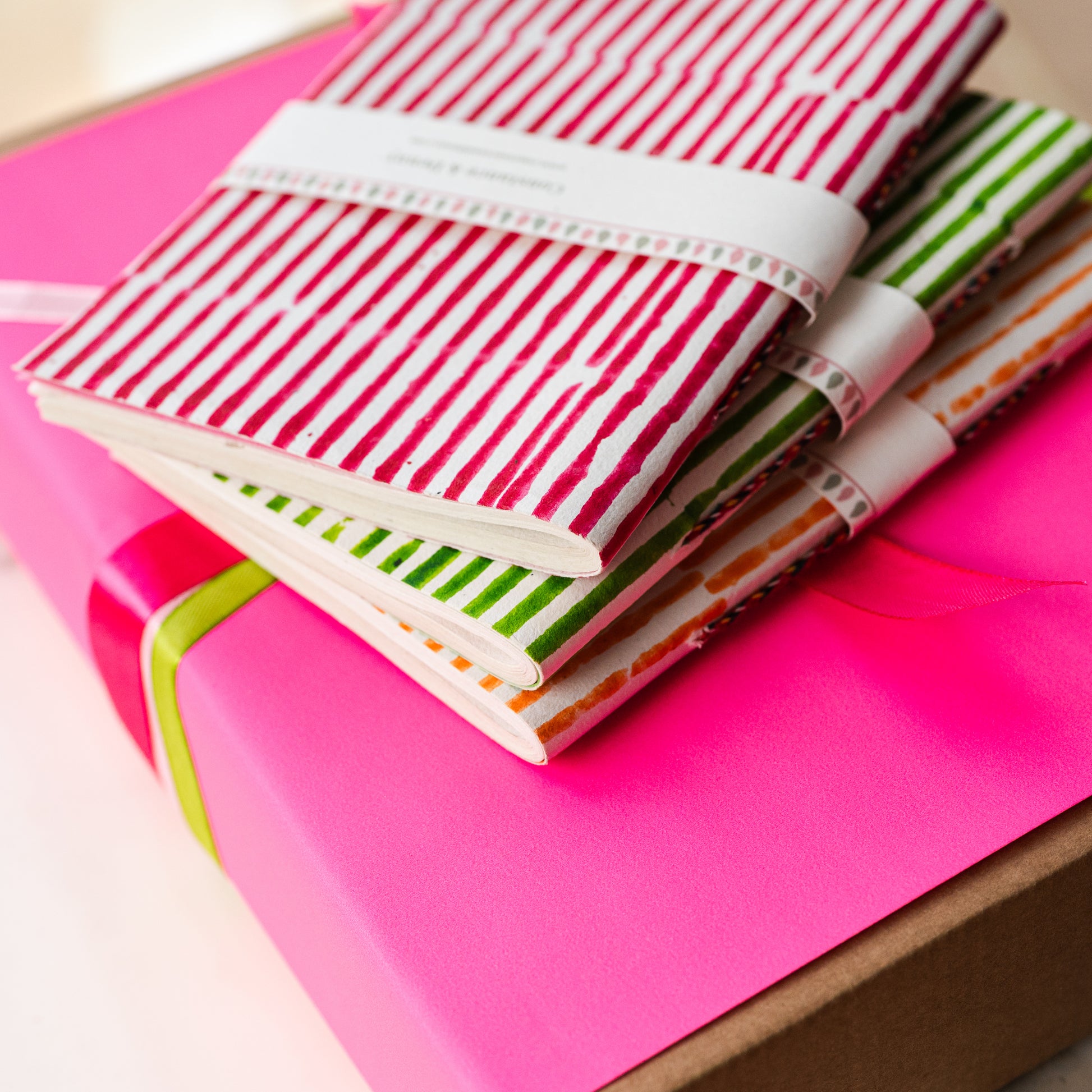 Colorful notebooks with striped patterns on a pink surface