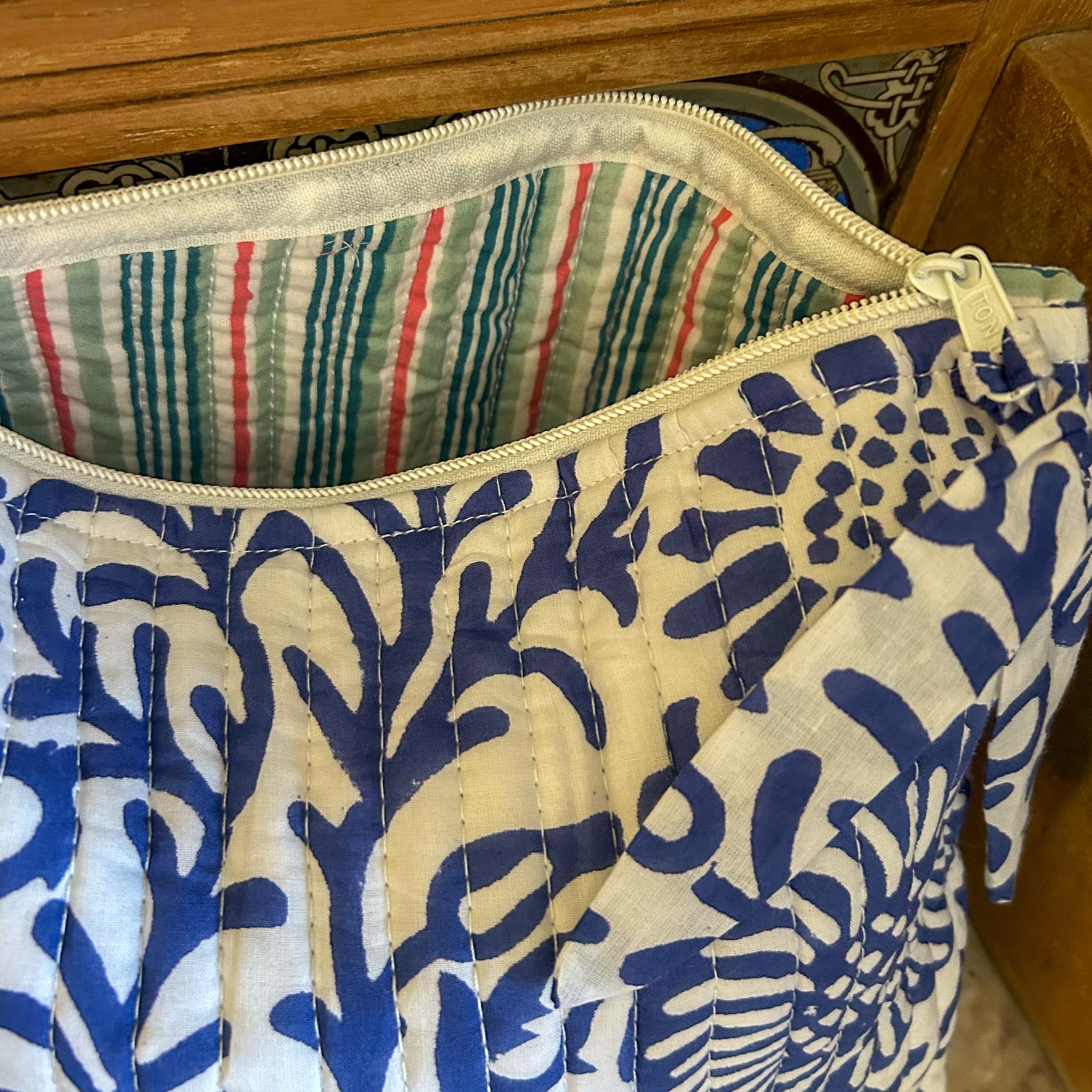 Fabric pouch with blue and white floral pattern on a wooden surface