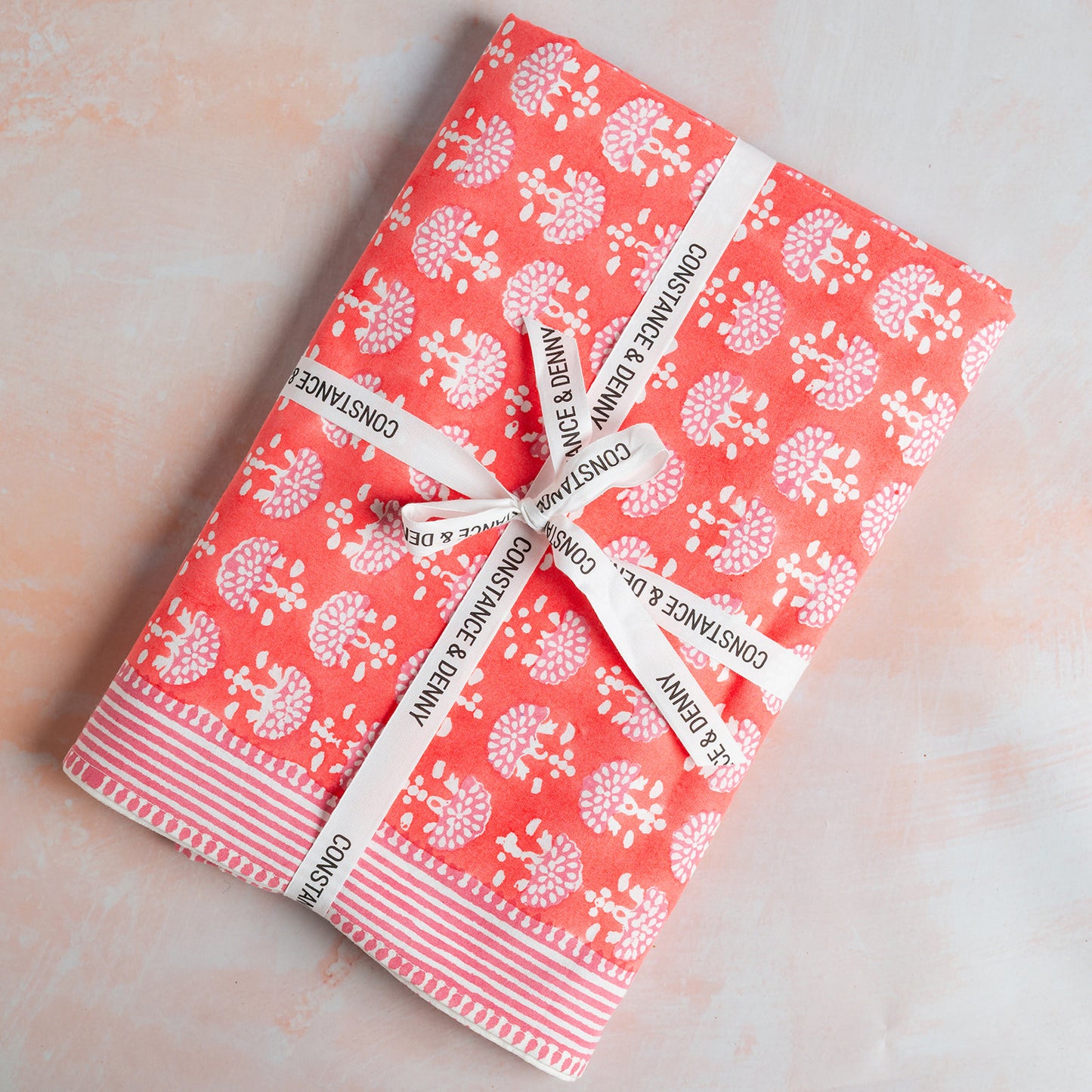 Two notebooks with a floral pattern and white ribbons on a light pink background