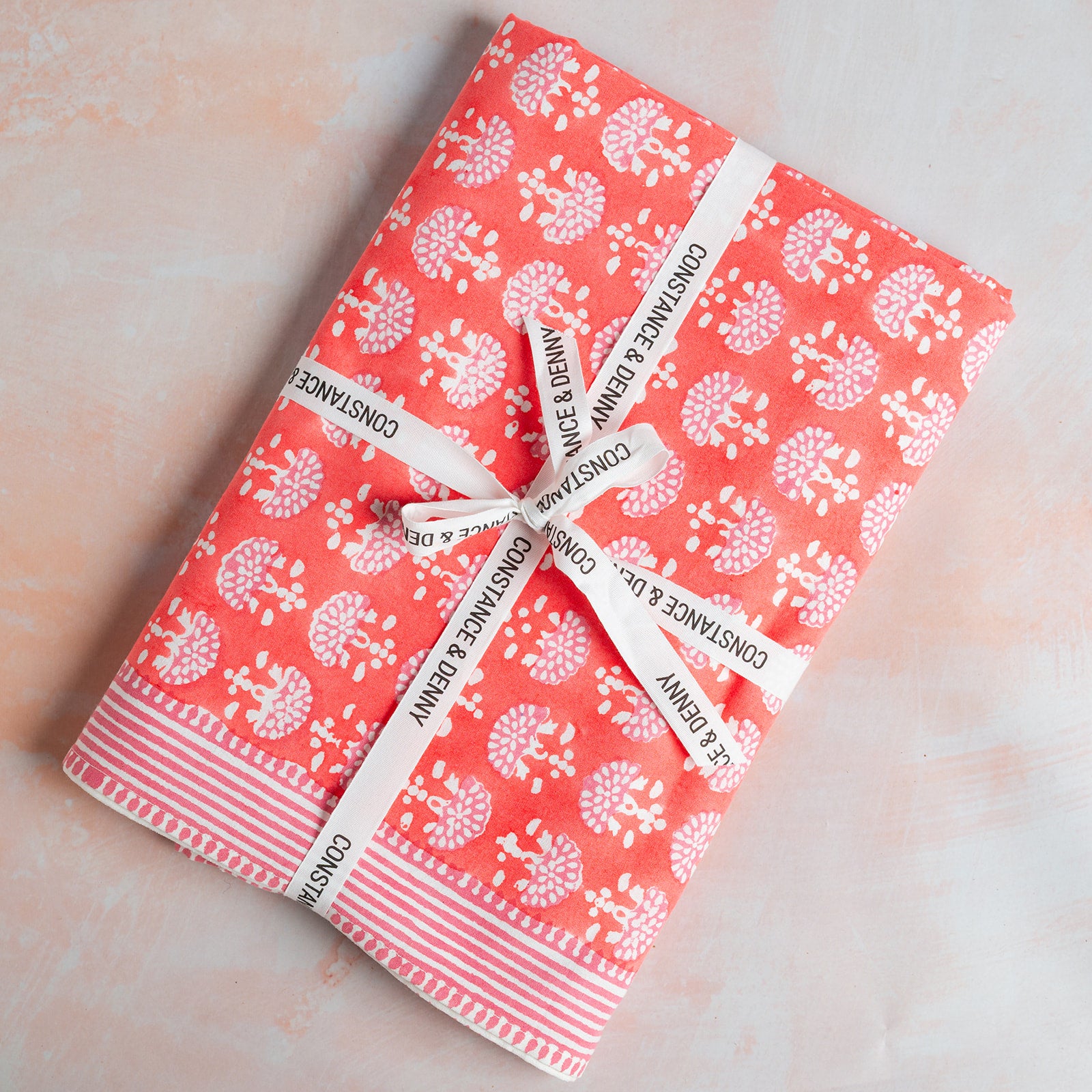 Two notebooks with a floral pattern and white ribbons on a light pink background