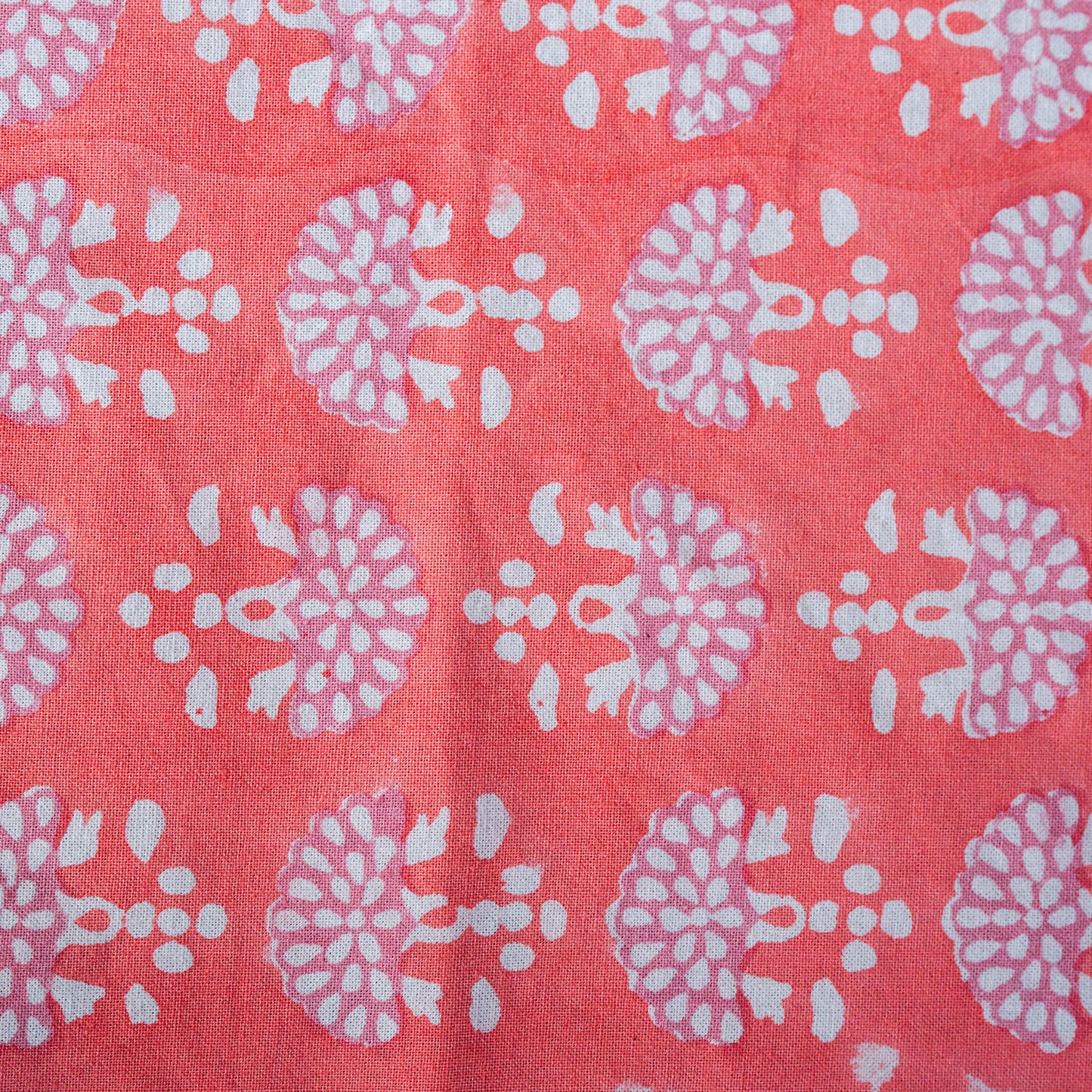 Patterned fabric with white floral designs on a pink background