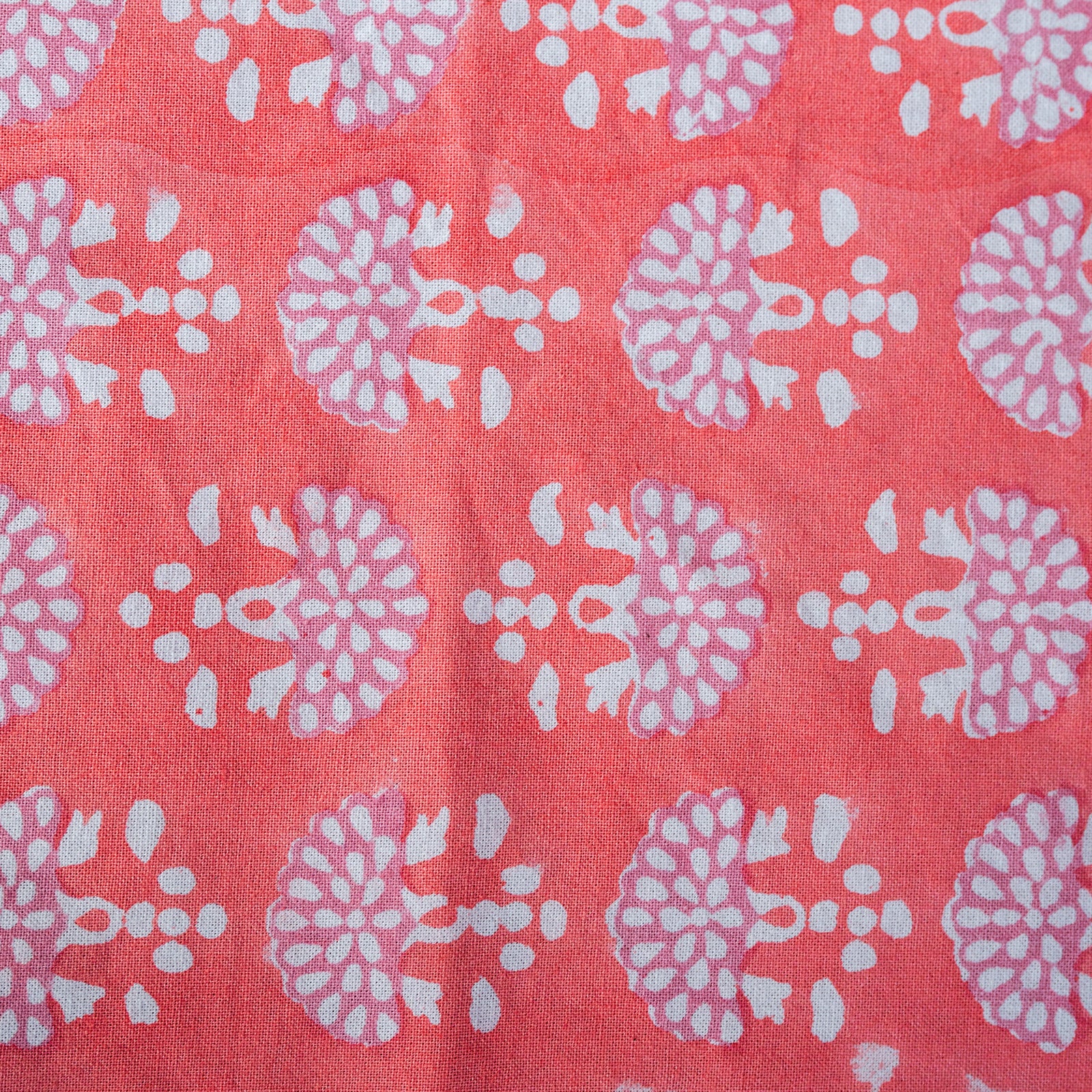 Patterned fabric with white floral designs on a pink background