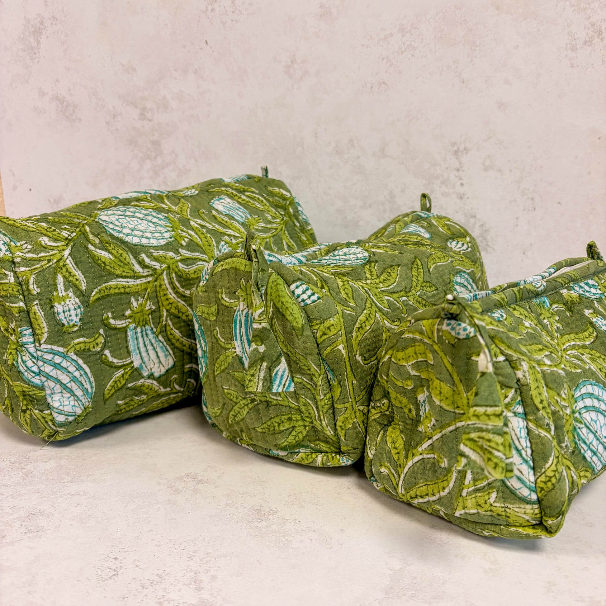 Green cosmetic bag with leaf pattern on a light grey background. small medium arge size. washbag