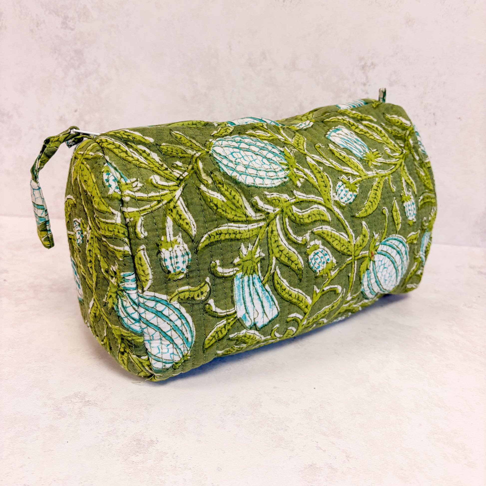 Green floral patterned cometic bag on a light grey background