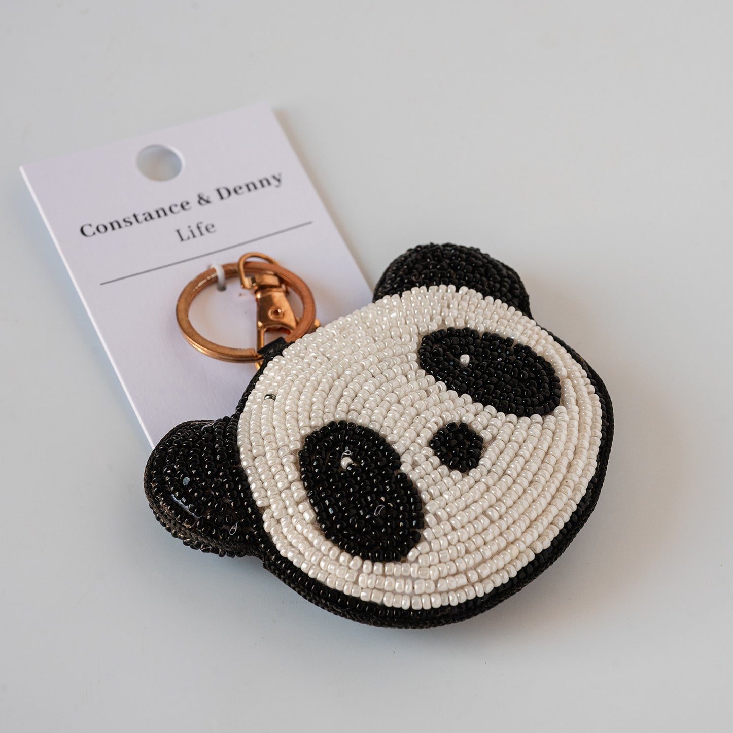A beaded panda head keychain with a gold-tone split ring and a white brand tag reading 'Constance & Denny Life', photographed on a clean white background.