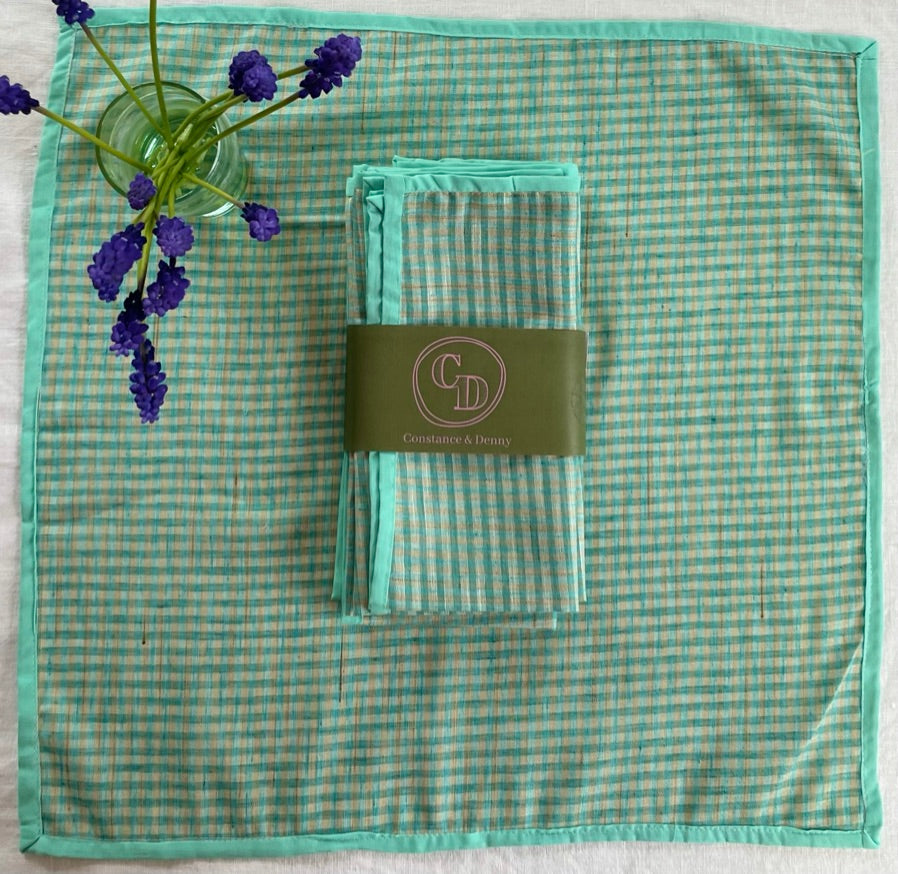 Green checkered napkin with a folded green checkered napkin and a visible brand label on a white background. gingham napkin