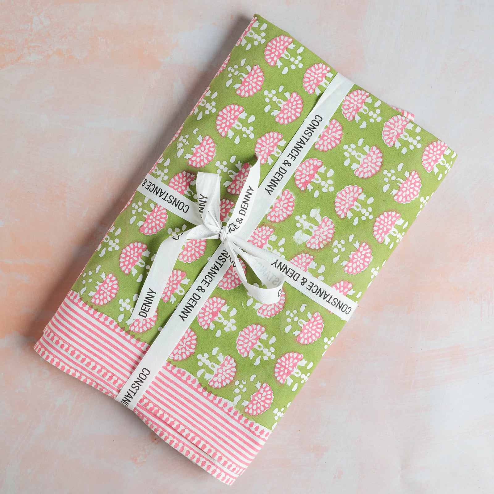Gift box with floral pattern and white ribbon on a light pink background