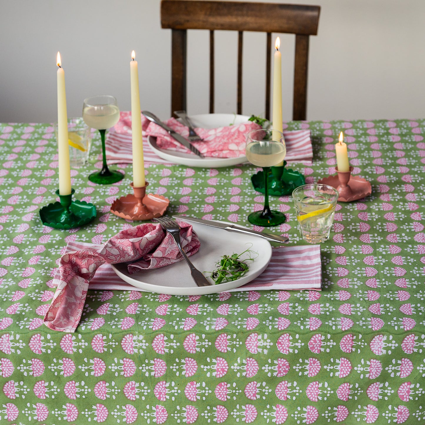 Dining table set with a floral tablecloth, candles, and cutlery.