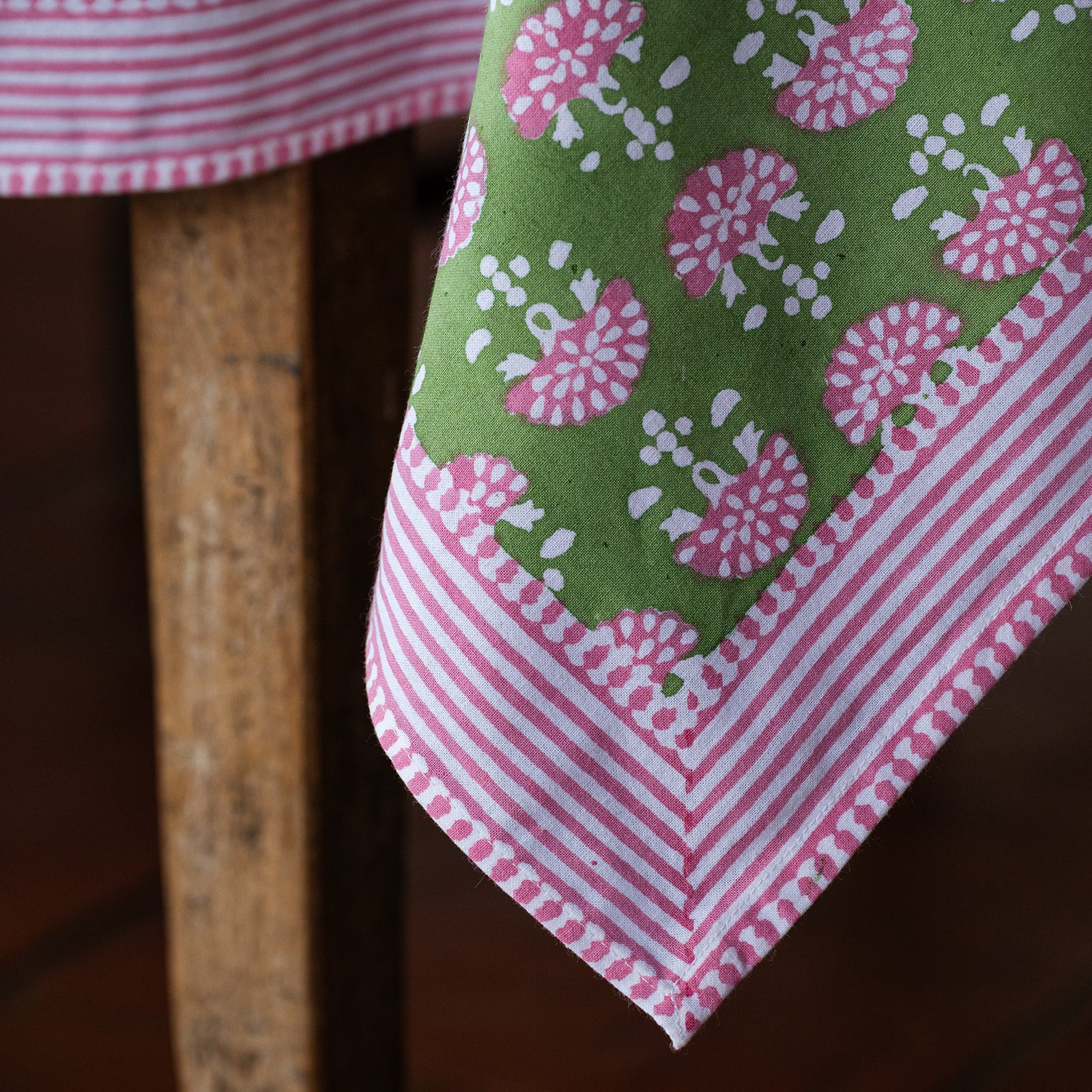 Close-up of a green and pink patterned fabric draped over a wooden surface.