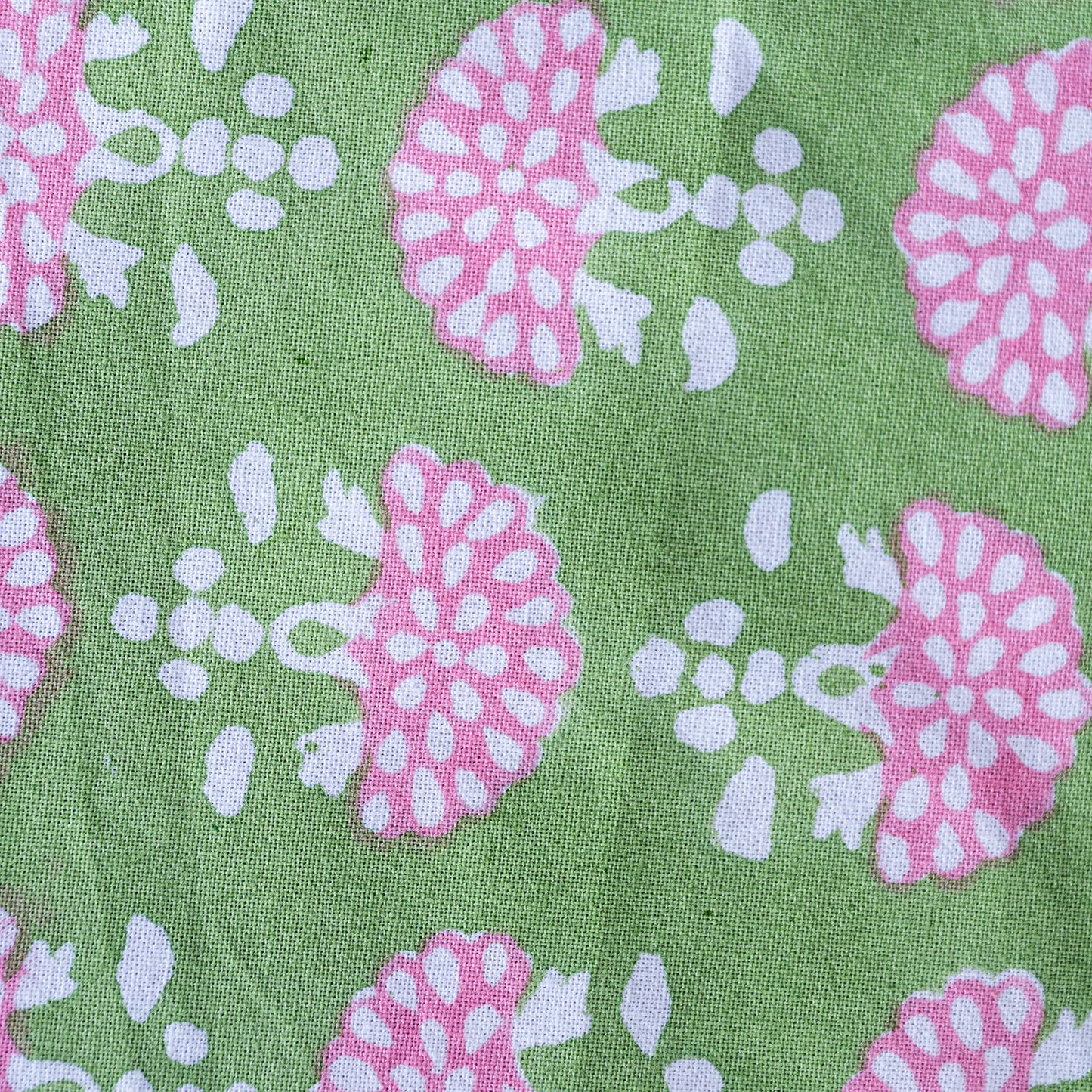 Patterned fabric with pink and white floral design on a green background