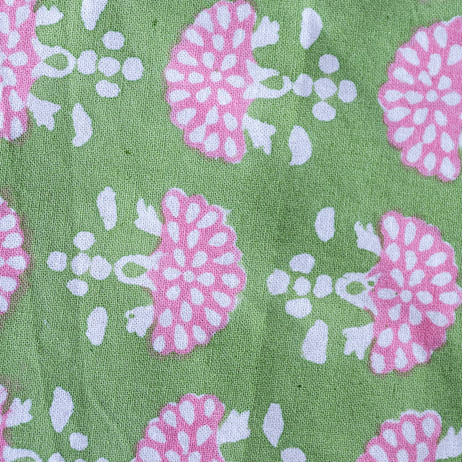 Patterned fabric with pink and white floral design on a green background