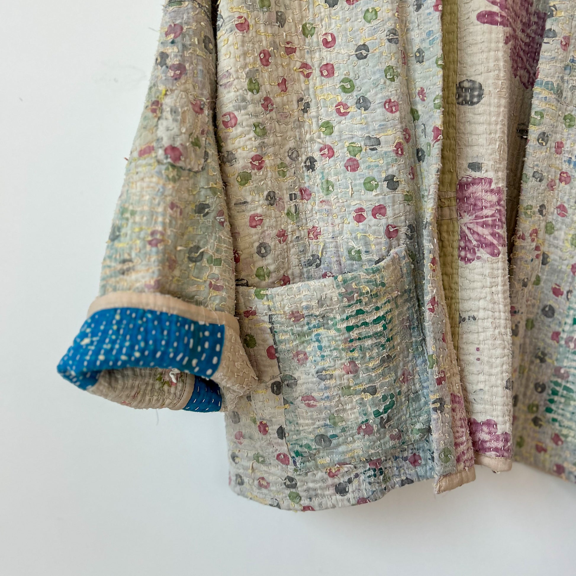 Textile with floral patterns and a pocket on a white background. intage-kantha-jacket-handmade-unique-42-sleeve