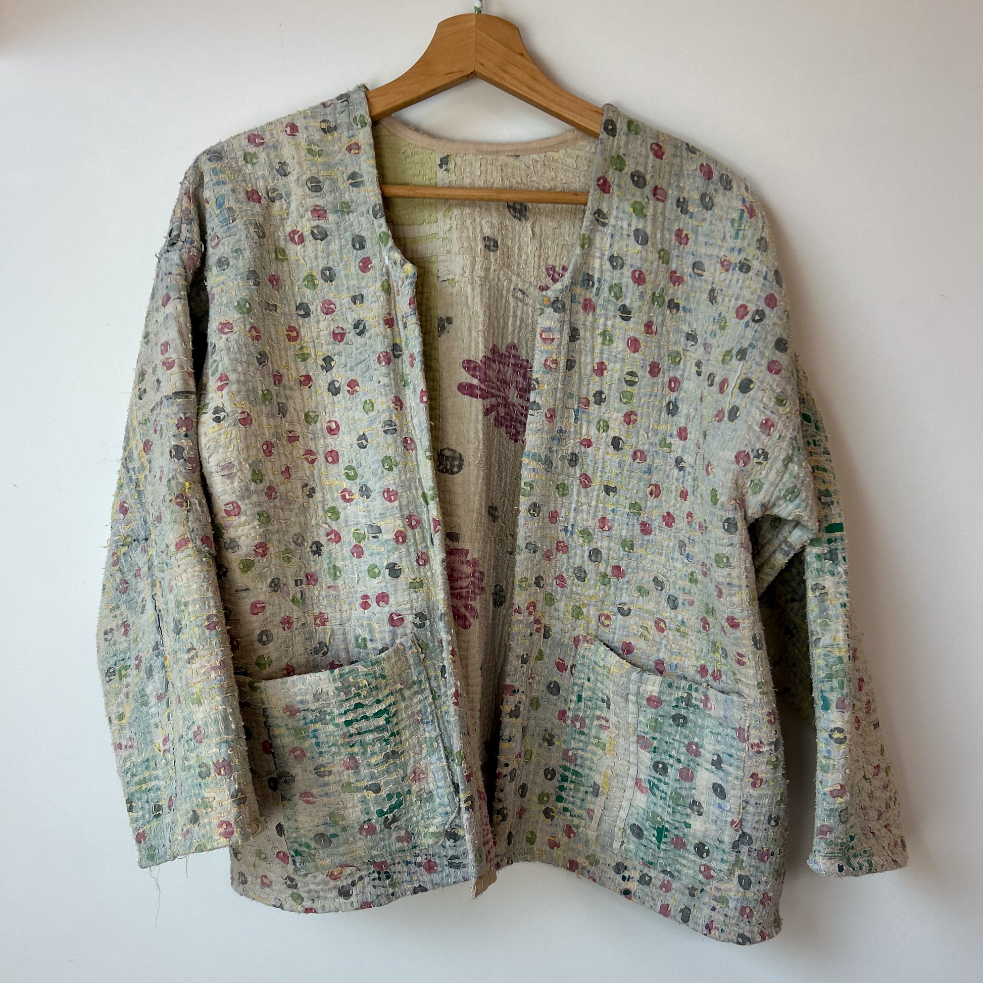 Floral patterned jacket on a hanger against a white background.  Vintage-kantha-jacket-handmade-unique-42-textured