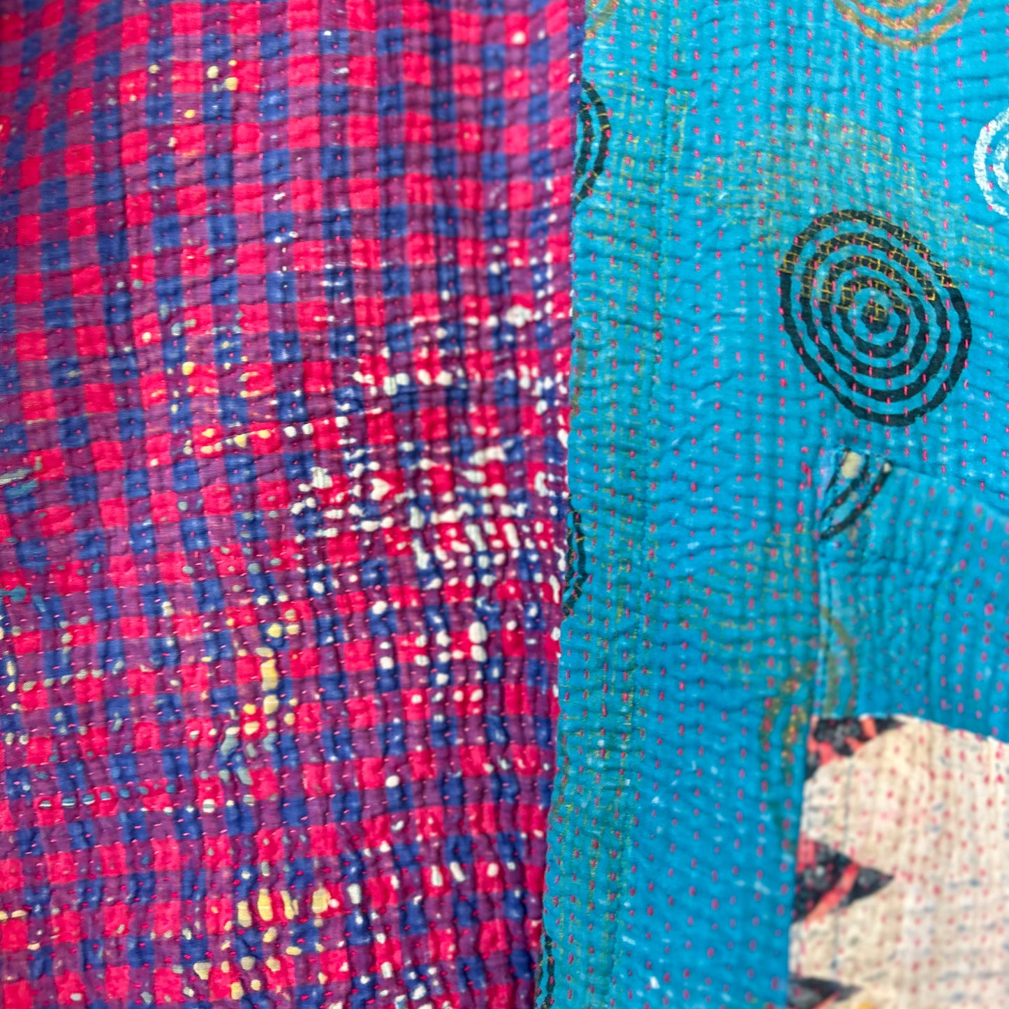 Close-up of two textured fabrics with a red and blue checkered pattern on the left and a blue fabric with circular patterns on the right.