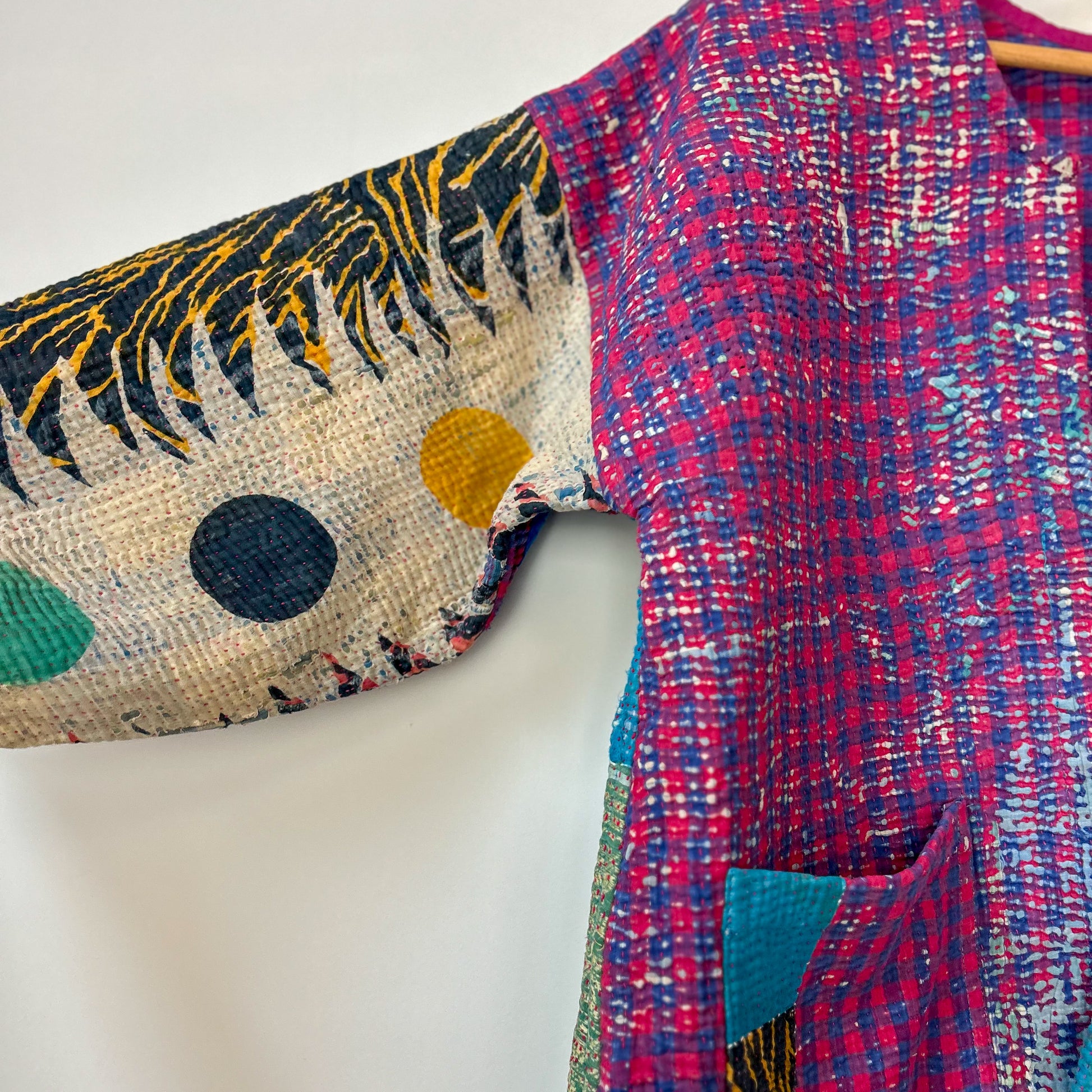 Colorful fabric with a floral pattern on one side and a plaid pattern on the other, on a white background. kantha-kacket-handmade-vintage-modern-colourful-blue-violet-33