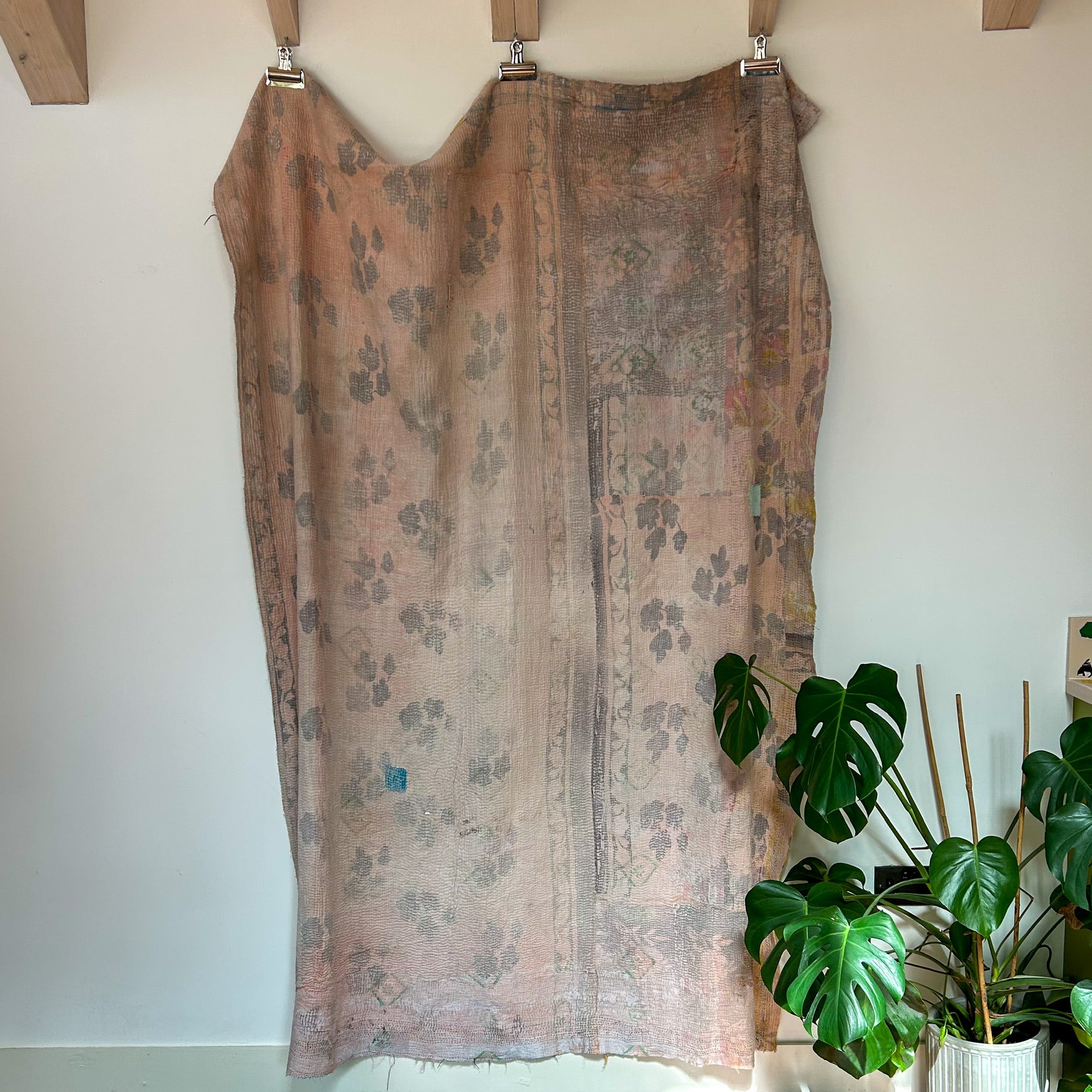 Floral patterned dress hanging on a rack with a plant in the background
