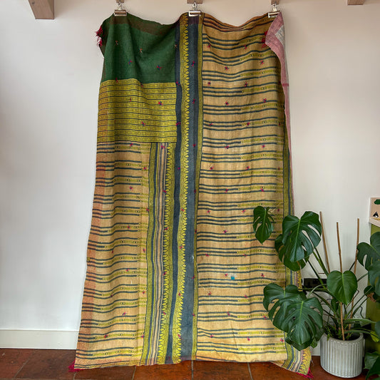 Two traditional sarees with green and yellow patterns draped over a wooden frame against a white wall. kantha-vintage-2035- hand-made-blanket-throw-textiles-wall-hanging