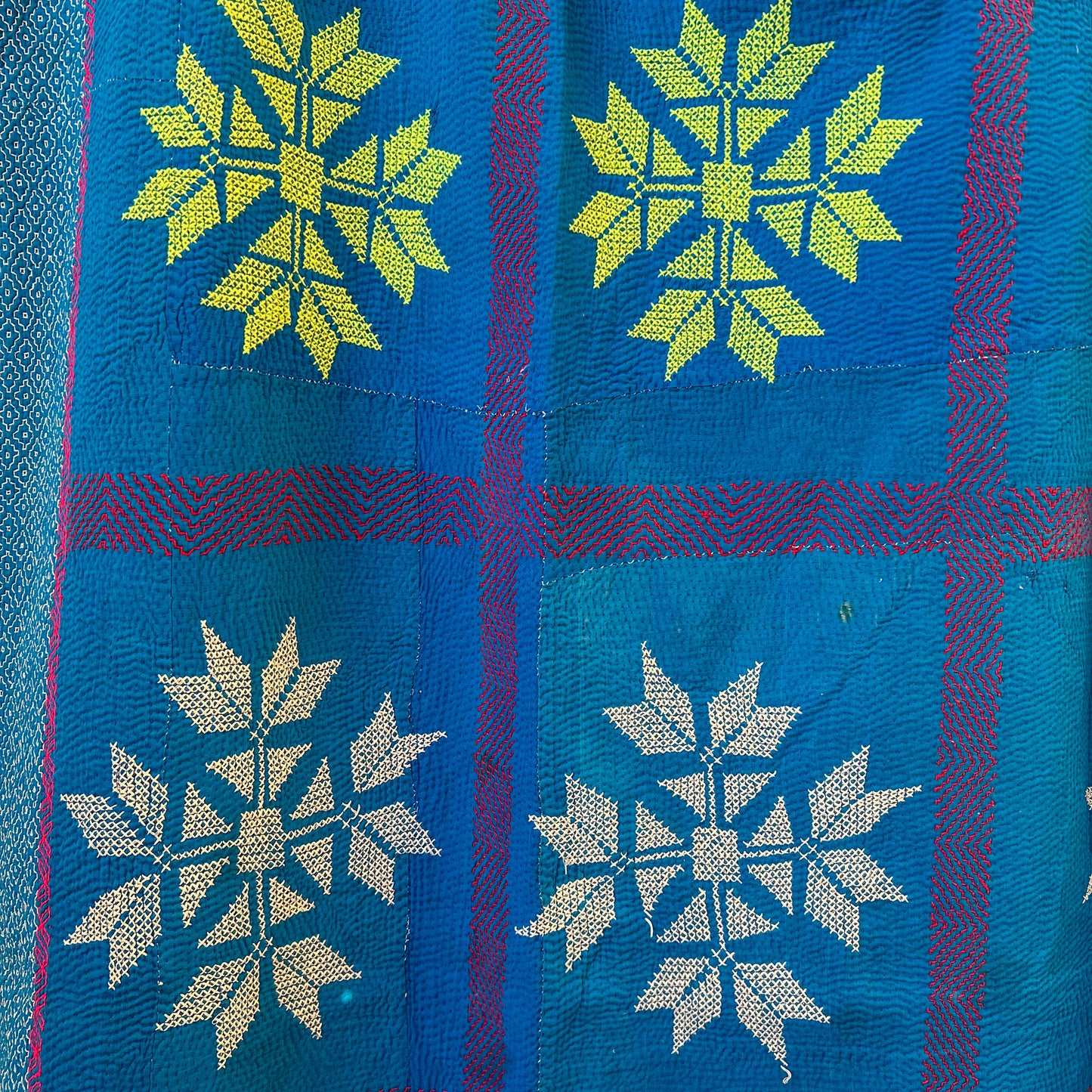 Textile with snowflake patterns in green, white, and blue on a blue background