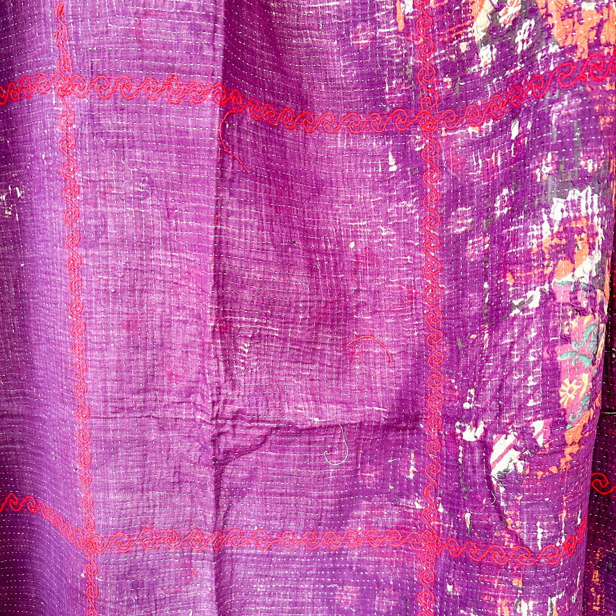 Close-up of a purple fabric with pink border and floral patterns