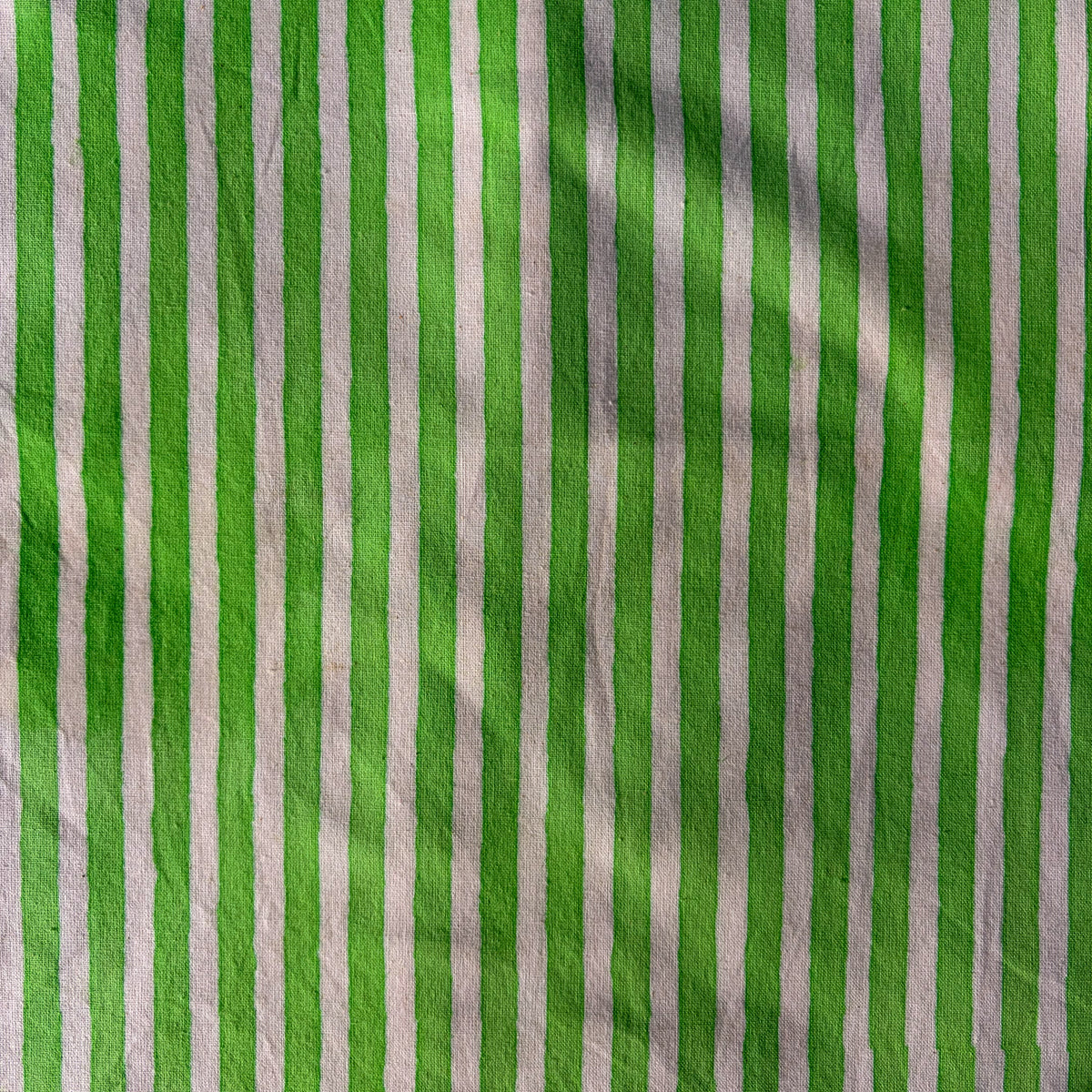 Green and white vertically striped fabric with a textured, slightly crinkled surface.