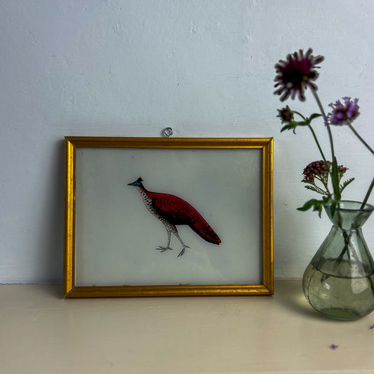 Framed artwork of a red bird on a white surface with a vase of flowers. indian-glass-painting-art-reverse-three-red-bird