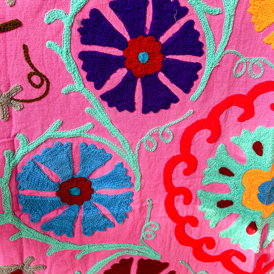 Close-up of colorful floral embroidery on a pink fabric background