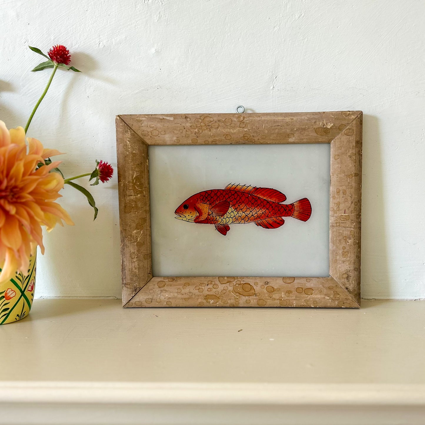 Framed artwork of a red fish on a white surface with flowers. onstance-and-denny-indian-reverse-glass-painting-boxed-packaging-hand-painted-artisan-art-red-fish