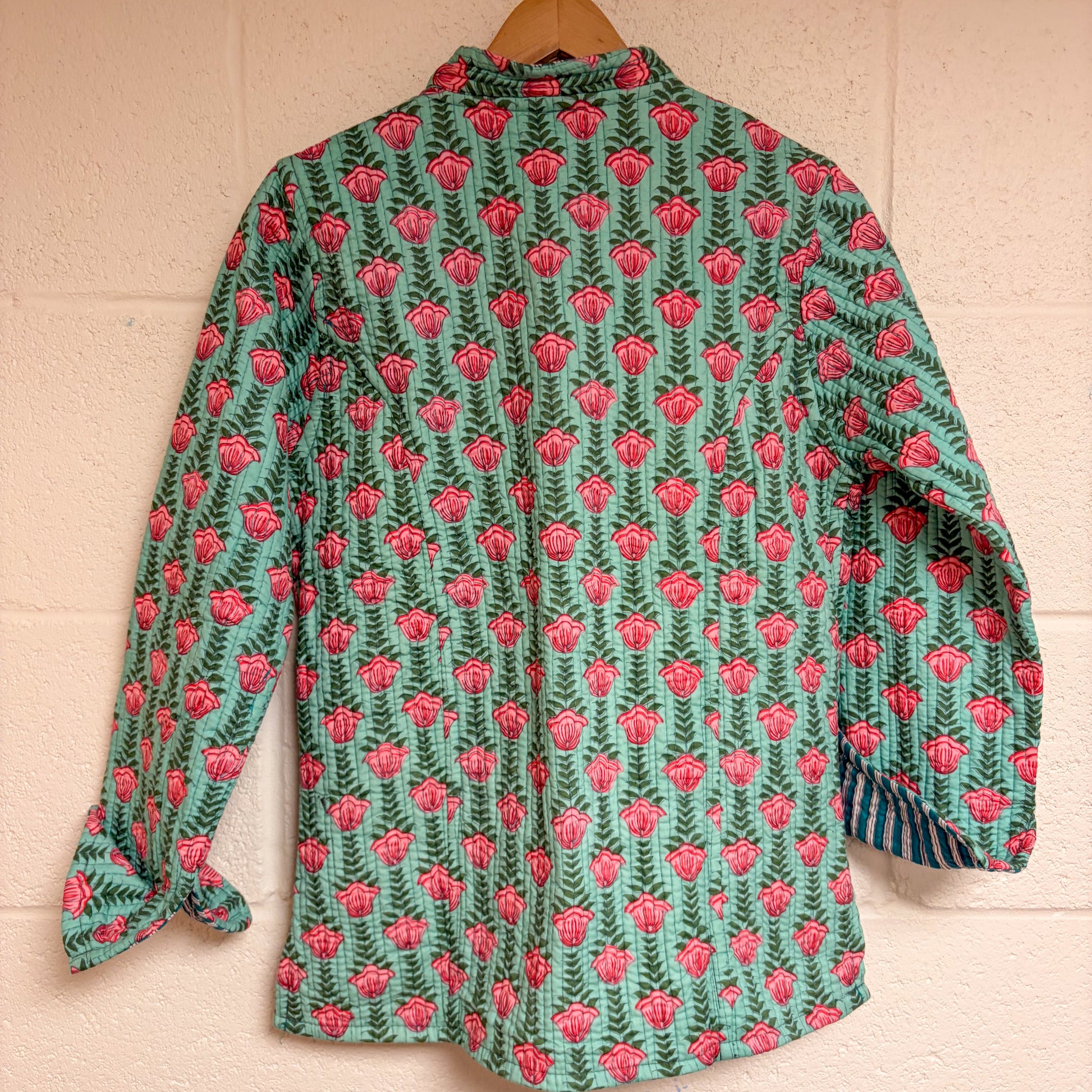 Floral patterned shirt on a wooden hanger against a beige wall.