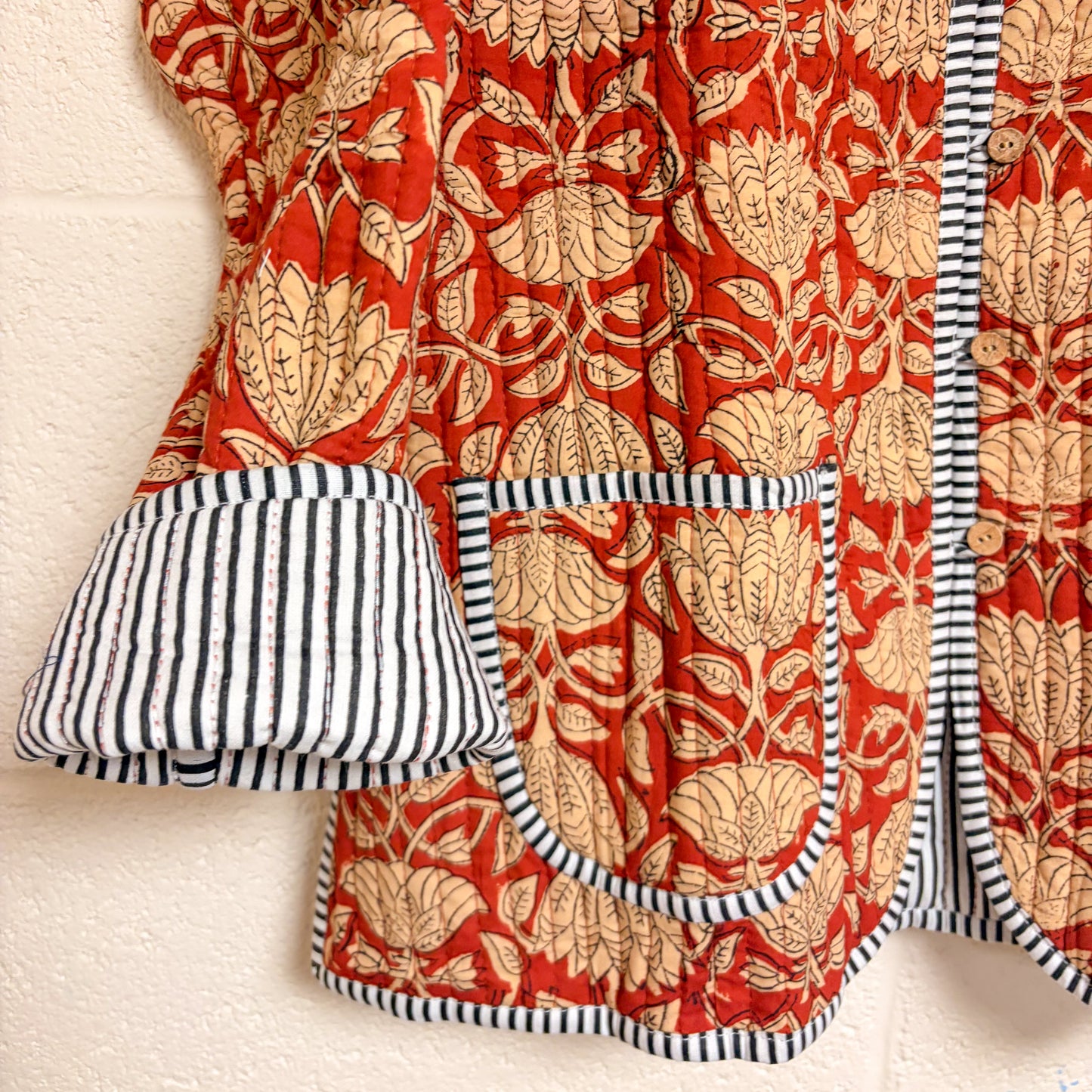 Red floral fabric with black and white striped trim on a textured surface