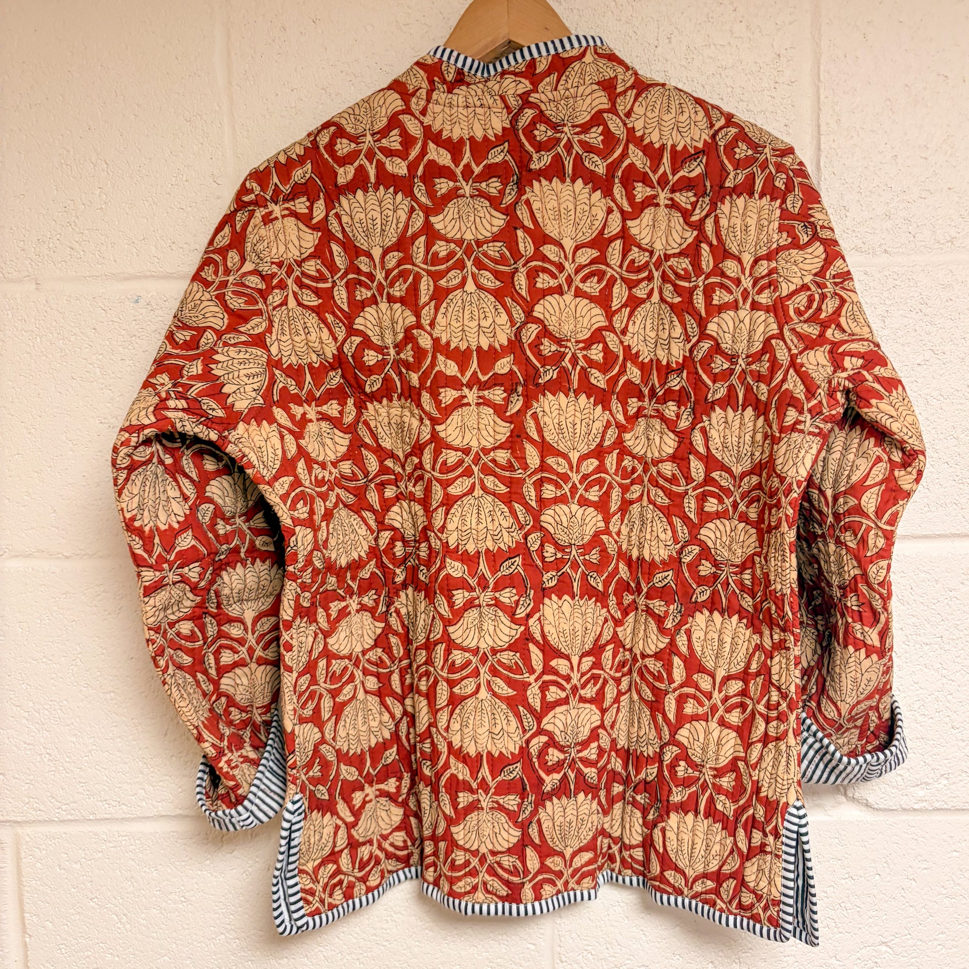Red and beige patterned shirt on a wooden hanger against a white wall