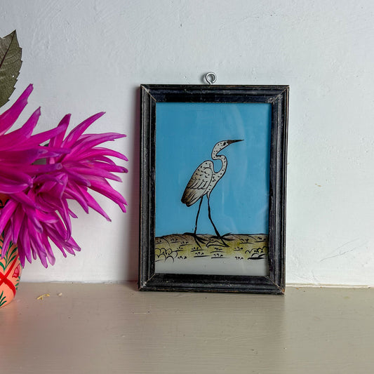 Framed artwork of a bird on a blue background next to pink flowers