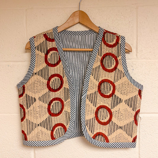  patterned vests hanging on a wooden hanger against a beige wall.