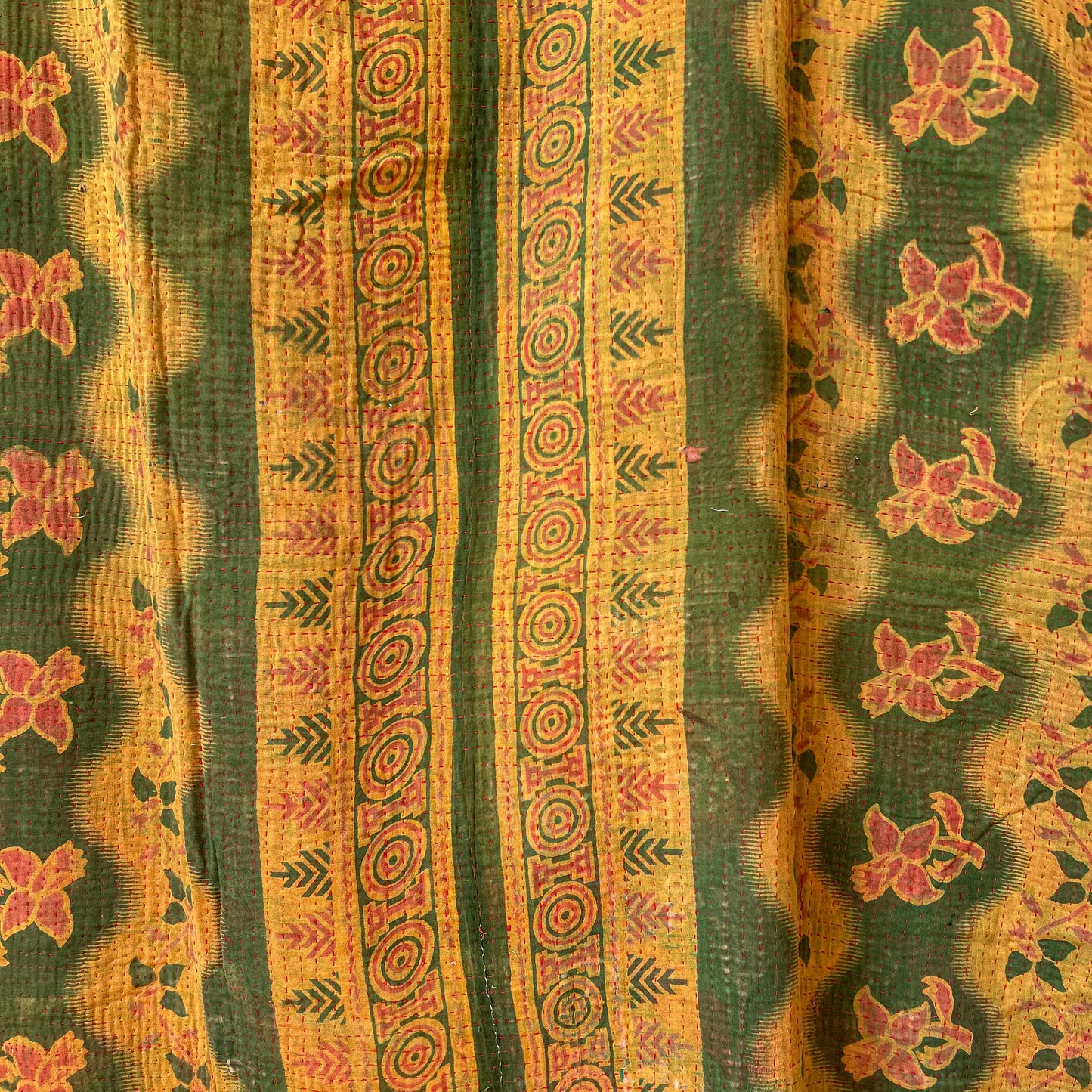 Decorative fabric with floral and geometric patterns in green and orange. Vintage-kantha-B-detail-blanket