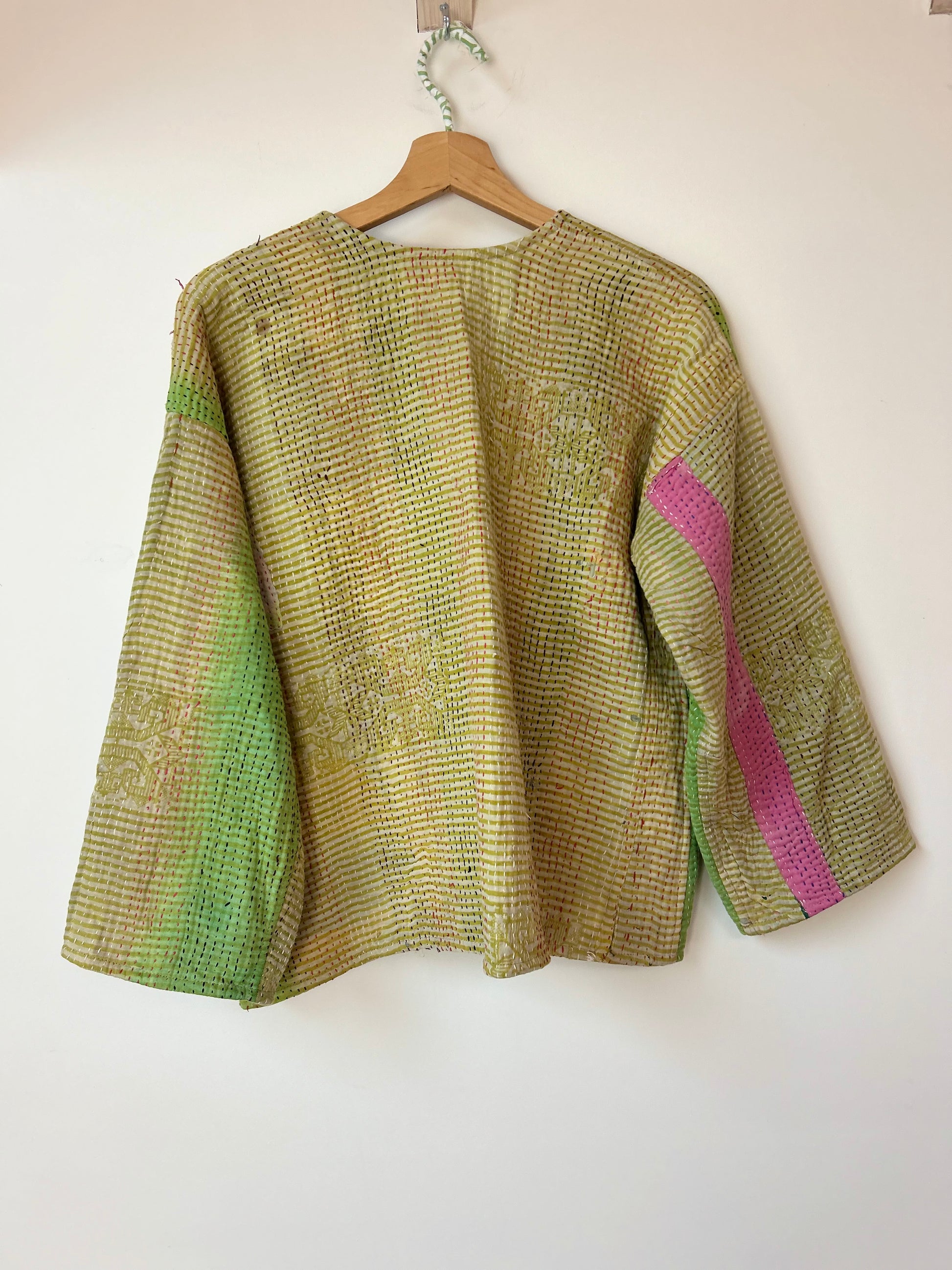 Textured green and pink jacket on a hanger against a white background. vintage-kantha-jacket-chartreuse-47-handmade-reverse