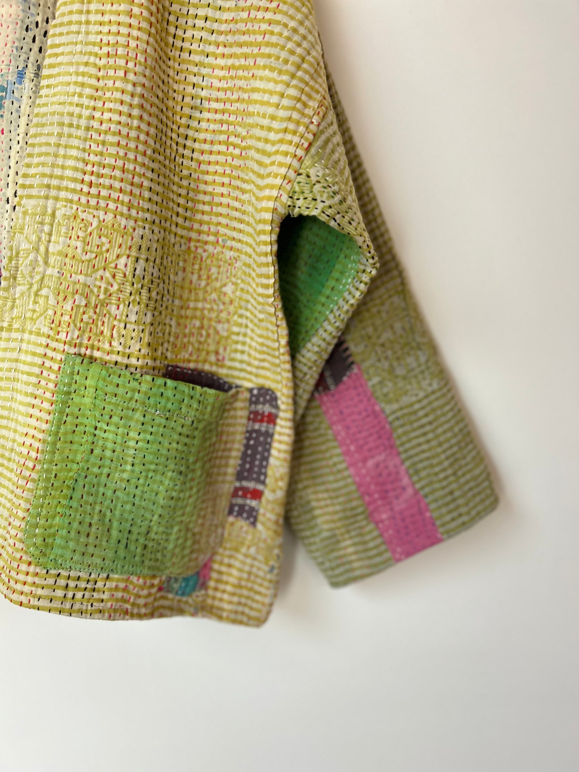 Textured fabric with green and pink patterns on a white background. vintage-kantha-jacket-chartreuse-47-handmade-sleeve