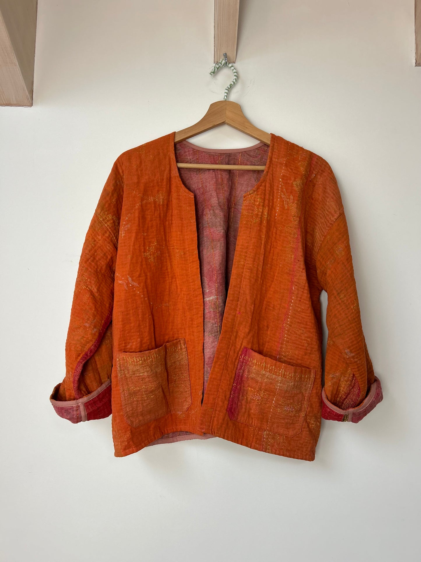 Orange jacket on a hanger against a white wall vintage-kantha-jacket-corange-48-handmade