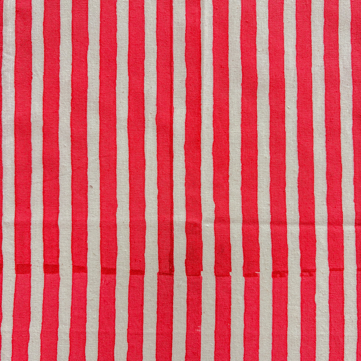 Red and off-white vertically striped fabric with a visible woven texture.